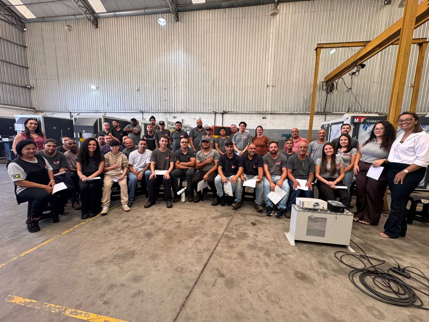 Equipe reunida em galpão industrial ao final de um treinamento